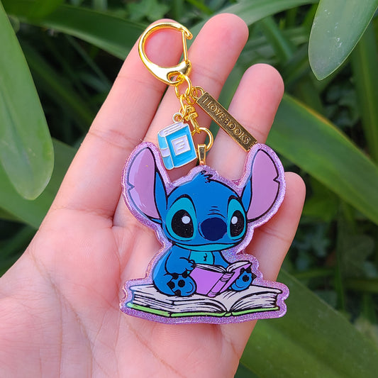Keychain shaped like a cartoon character held in a hand with a green leafy background