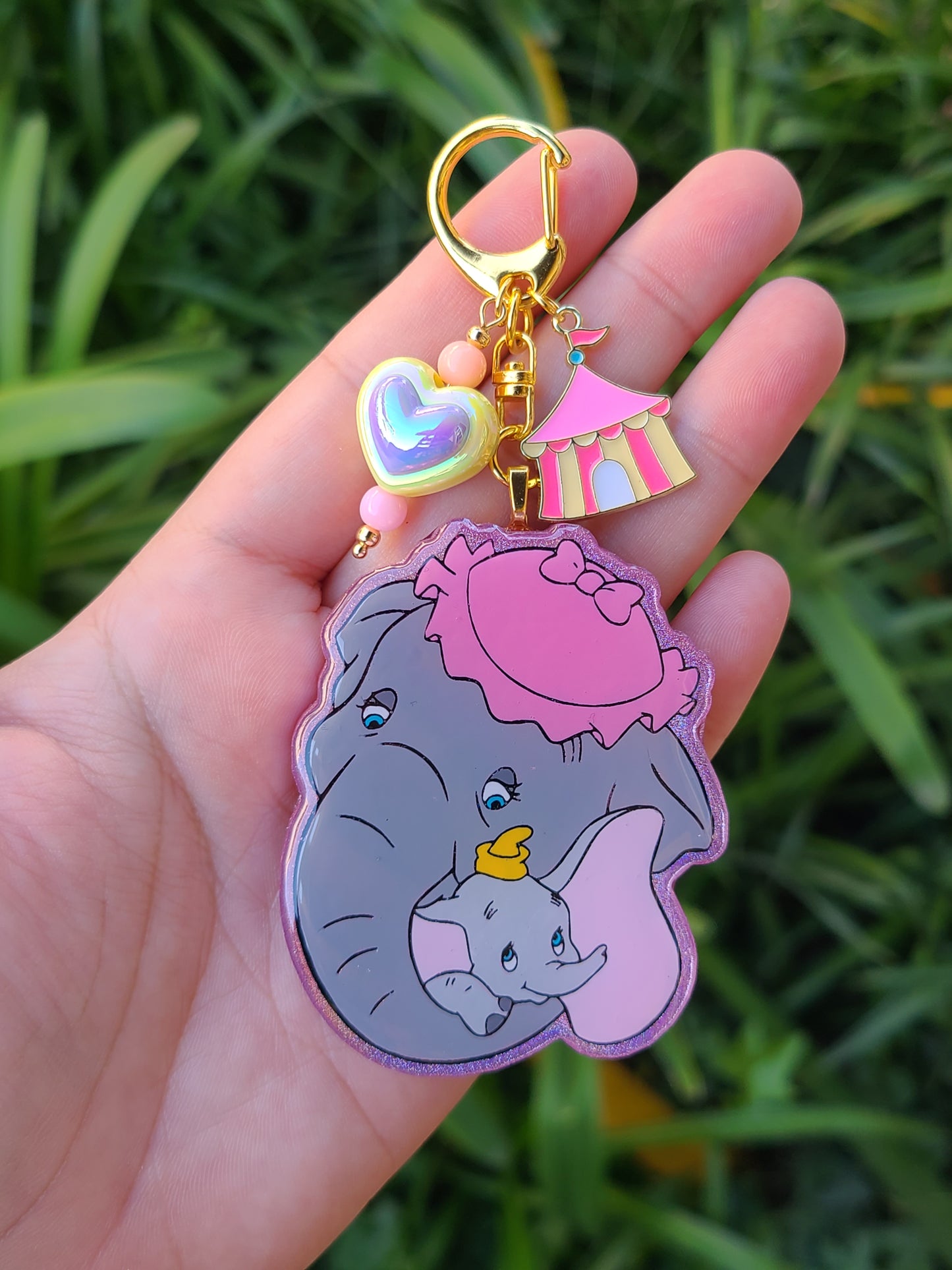 Keychain with cartoon elephant design held in a hand against a grassy background